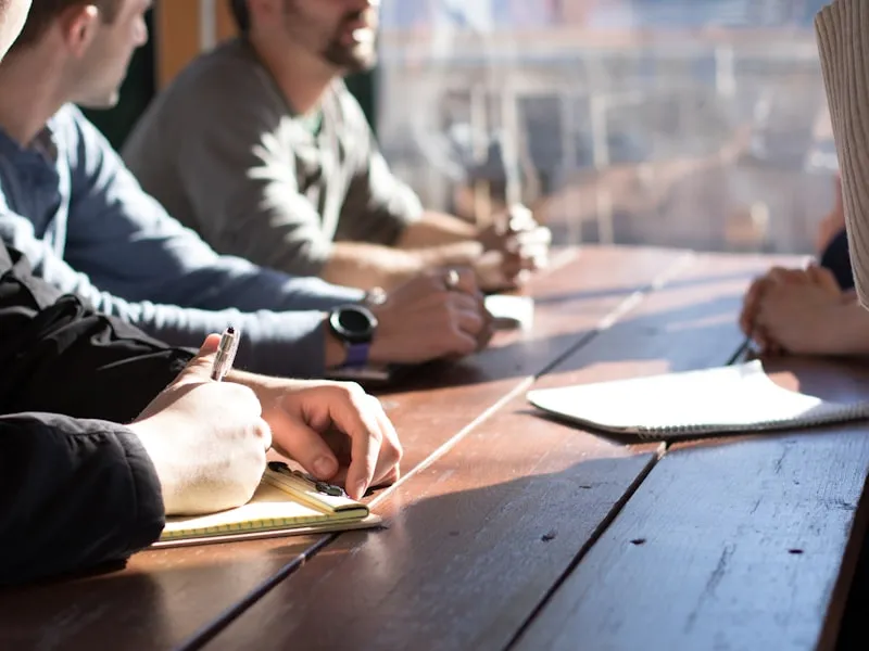 Team collaborating at a table with notebooks and warm natural light